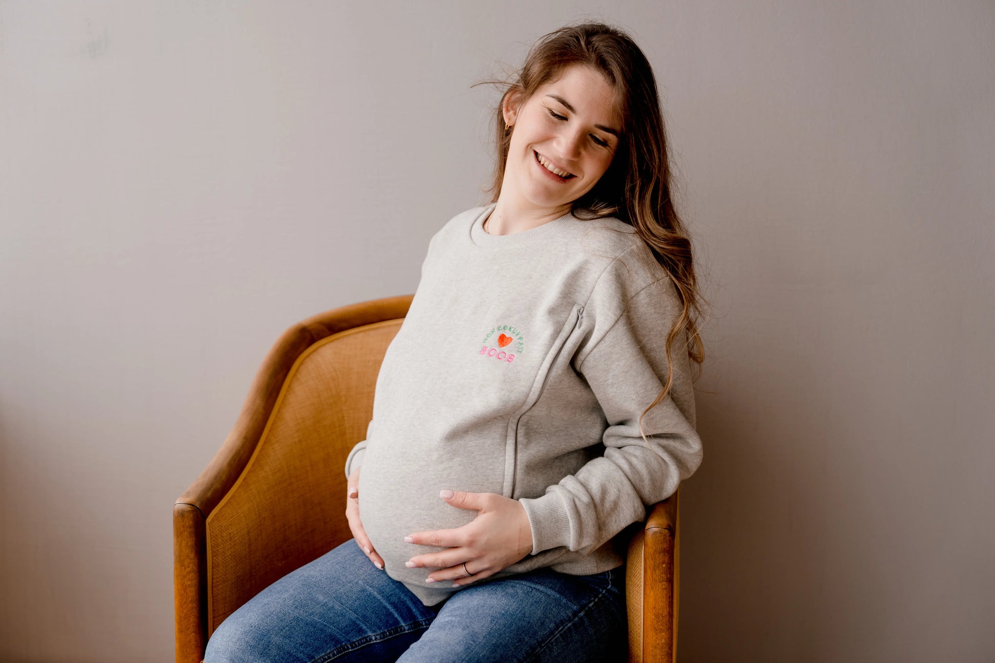 future maman enceinte qui porte son sweat de grossesse gris chiné en coton, brodé au coeur "Mon Coeur fait boob". Sweat d'inspiration des années 90s, est polyvalent et peut être porté par les futures mamans enceinte pendant leur grossesse et aussi après l'accouchement pour allaiter bébé. Deux zips de la marque YKK de chaque côté de la poitrine permettent d'accéder au sein et de nourrir facilement, simplement et discrètement votre bébé. Un sweat moderne, tendance grâce à sa coupe loose confortable féminine