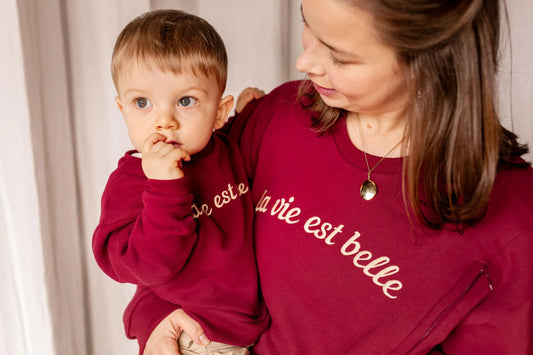 Duo de sweats en coton de couleur bordeaux assortis pour maman et bébé avec une broderie « La vie est belle » identique. Le sweat allaitement pour maman comporte des zips discrets et solides faciles à ouvrir d'une seule main.