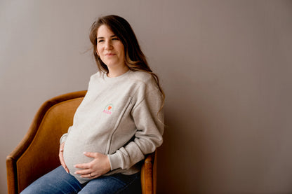 future maman enceinte qui porte son sweat de grossesse gris chiné en coton, brodé au coeur "Mon Coeur fait boob". Sweat d'inspiration des années 90s, est polyvalent et peut être porté par les futures mamans enceinte pendant leur grossesse et aussi après l'accouchement pour allaiter bébé. Deux zips de la marque YKK de chaque côté de la poitrine permettent d'accéder au sein et de nourrir facilement, simplement et discrètement votre bébé. Un sweat moderne, tendance grâce à sa coupe loose confortable féminine