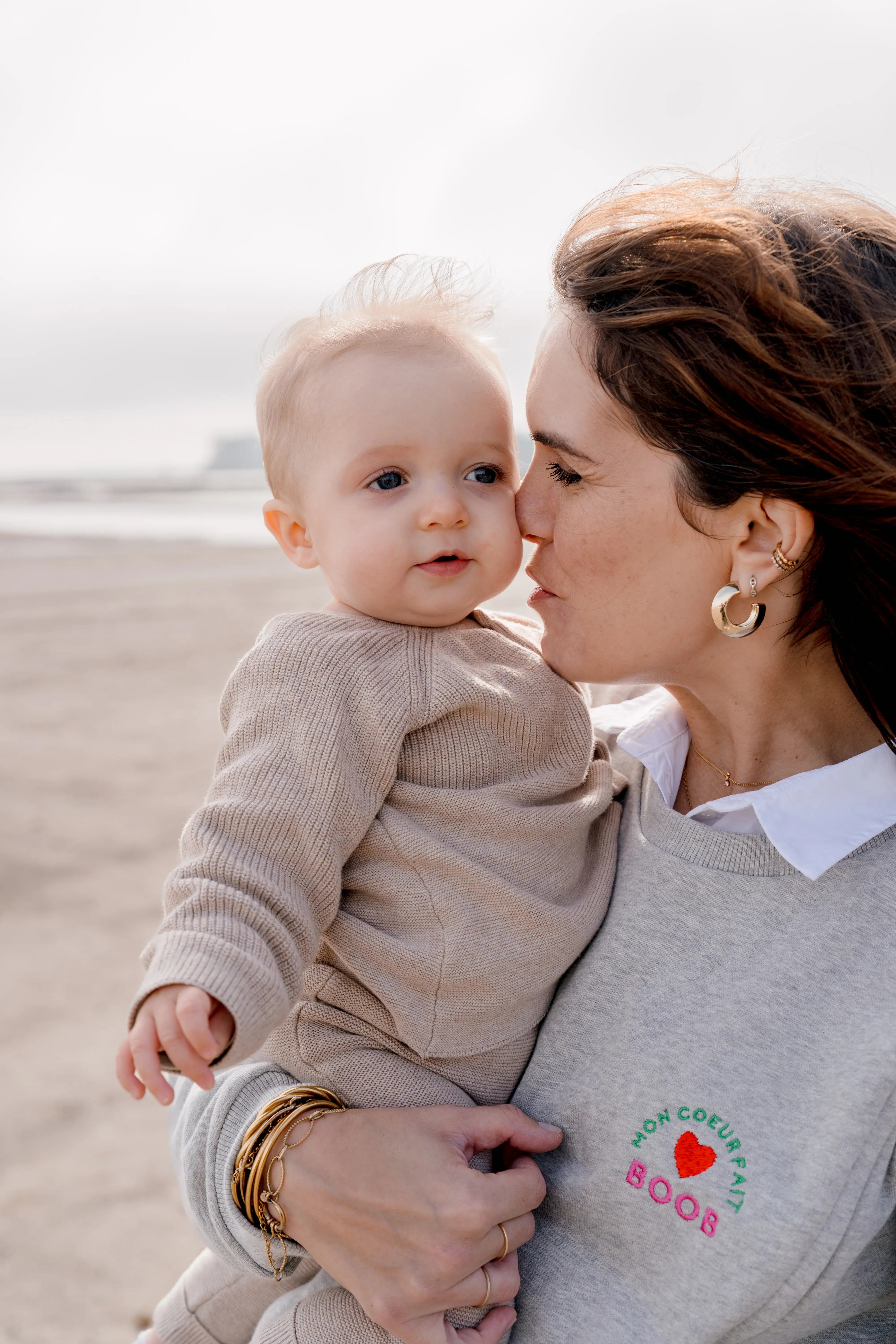 maman qui embrasse son bébé, portant son sweat maternité gris chiné en coton, brodé au coeur 