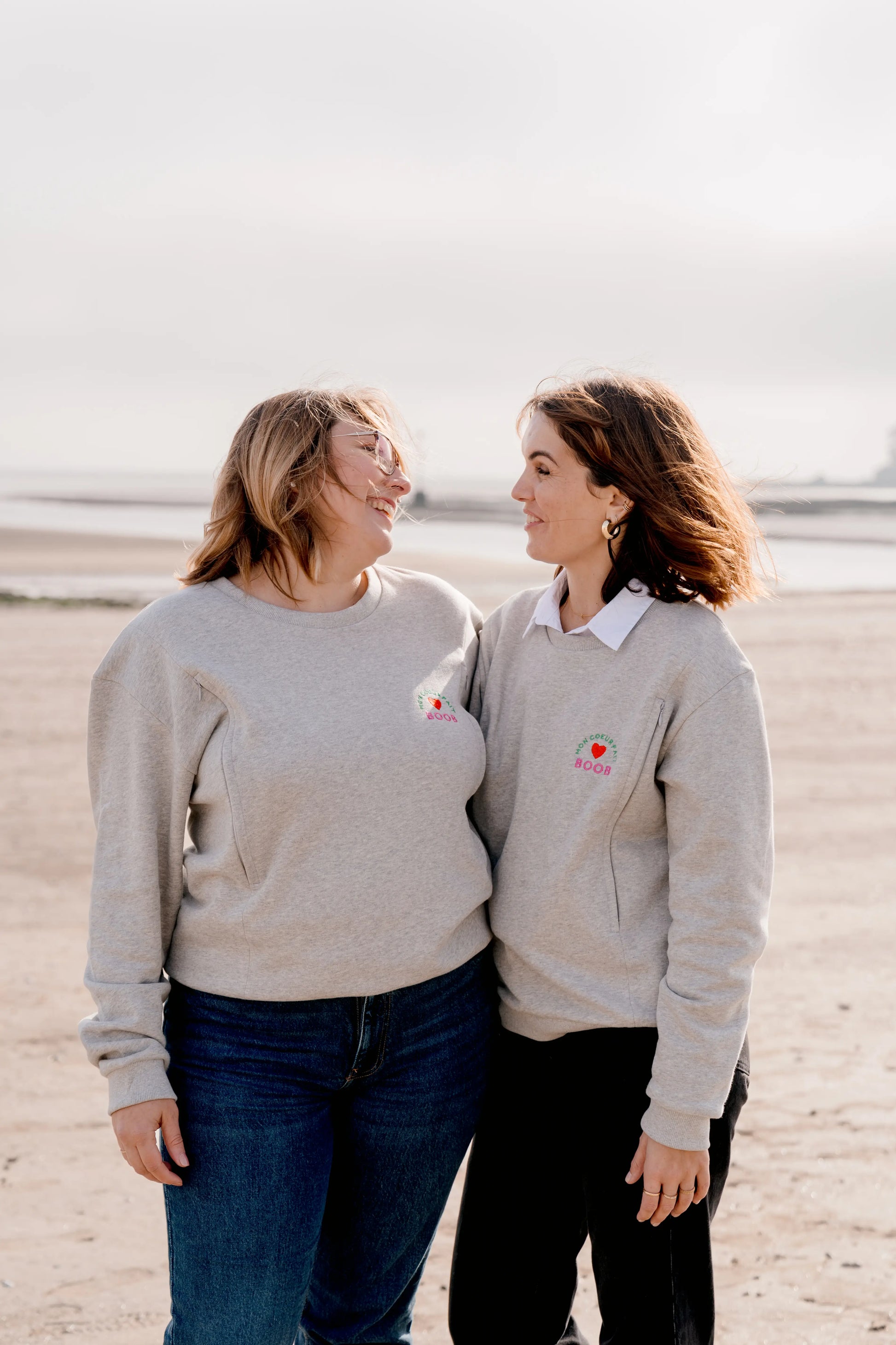 pull d'allaitement ou sweat de grossesse gris chiné en coton, brodé au coeur "Mon Coeur fait boob". Sweat d'inspiration des années 90s, est polyvalent et peut être porté par les futures mamans enceinte pendant leur grossesse et aussi après l'accouchement pour allaiter bébé. Deux zips de la marque YKK de chaque côté de la poitrine permettent d'accéder au sein et de nourrir facilement, simplement et discrètement votre bébé. de la taille S au XL pour toutes les tailles oversize.