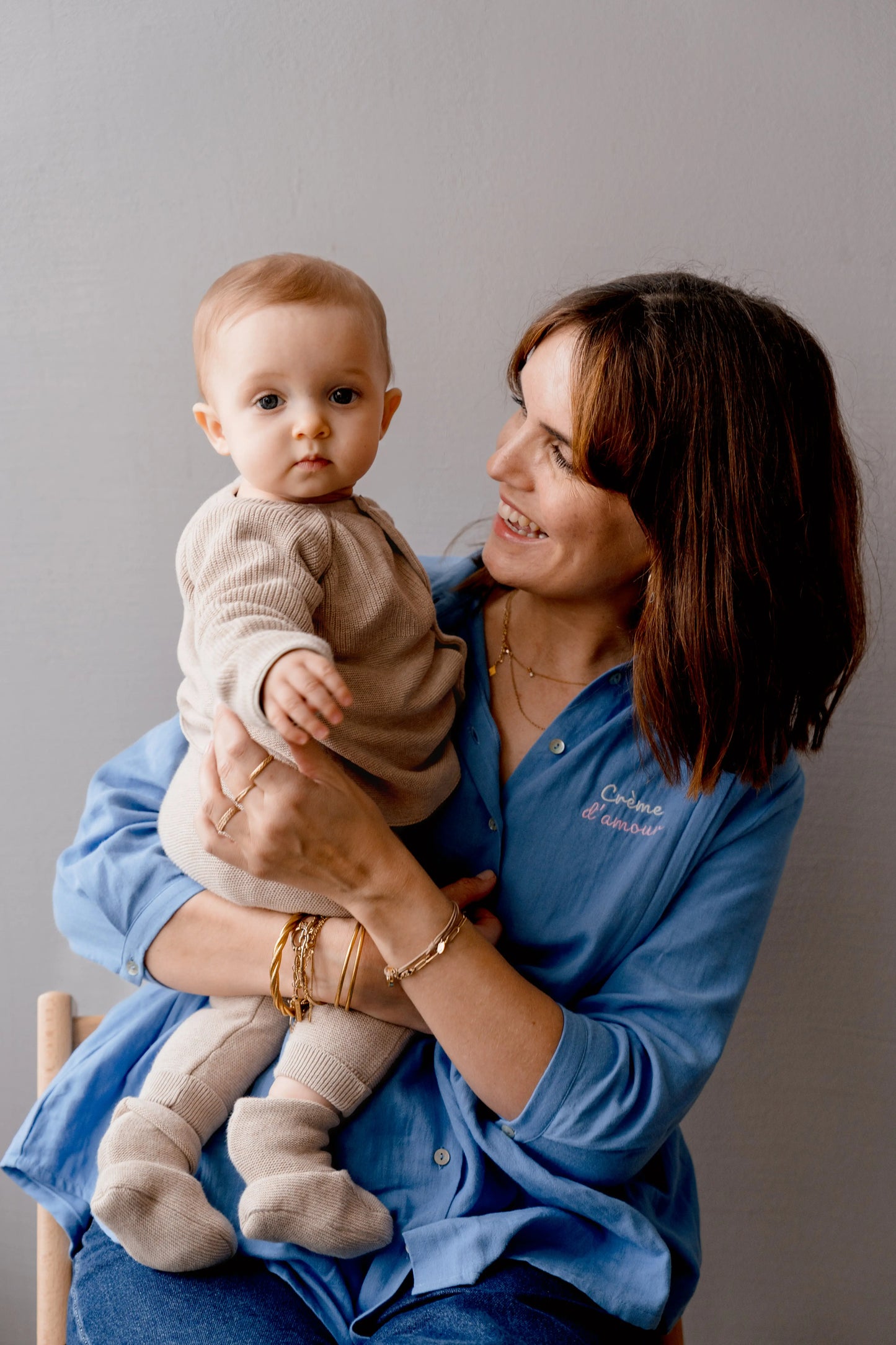 Jeune maman et son bébé. La maman porte une Blouse bohème bleu ciel en gaze de coton pour la grossesse et l'allaitement. Pour les mamans enceintes ou allaitantes. avec des zips de la marque YKK de chaque côté de la poitrine afin de nourrir facilement, rapidement et discrètement votre bébé. Broderie au coeur et boutons nacrés pour un style élégant et féminin.