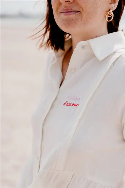 Blouse de Grossesse et Allaitement "Crème d'Amour" de la marque LIMKY. Une blouse chemisier de couleur crème, pour accompagner maman à chaque étape de sa maternité, dotée de zips discrets et solides pour faciliter l'allaitement de bébé. Une coupe flatteuse, un tissu absorbant en gaze de coton, avec une jolie broderie au coeur "crème d'amour". Idéal en cas de petite fuite de lait maternel. Un cadeau de naissance chic et idéal pour les jeunes et futures mamans qui fêtent leur baby shower !