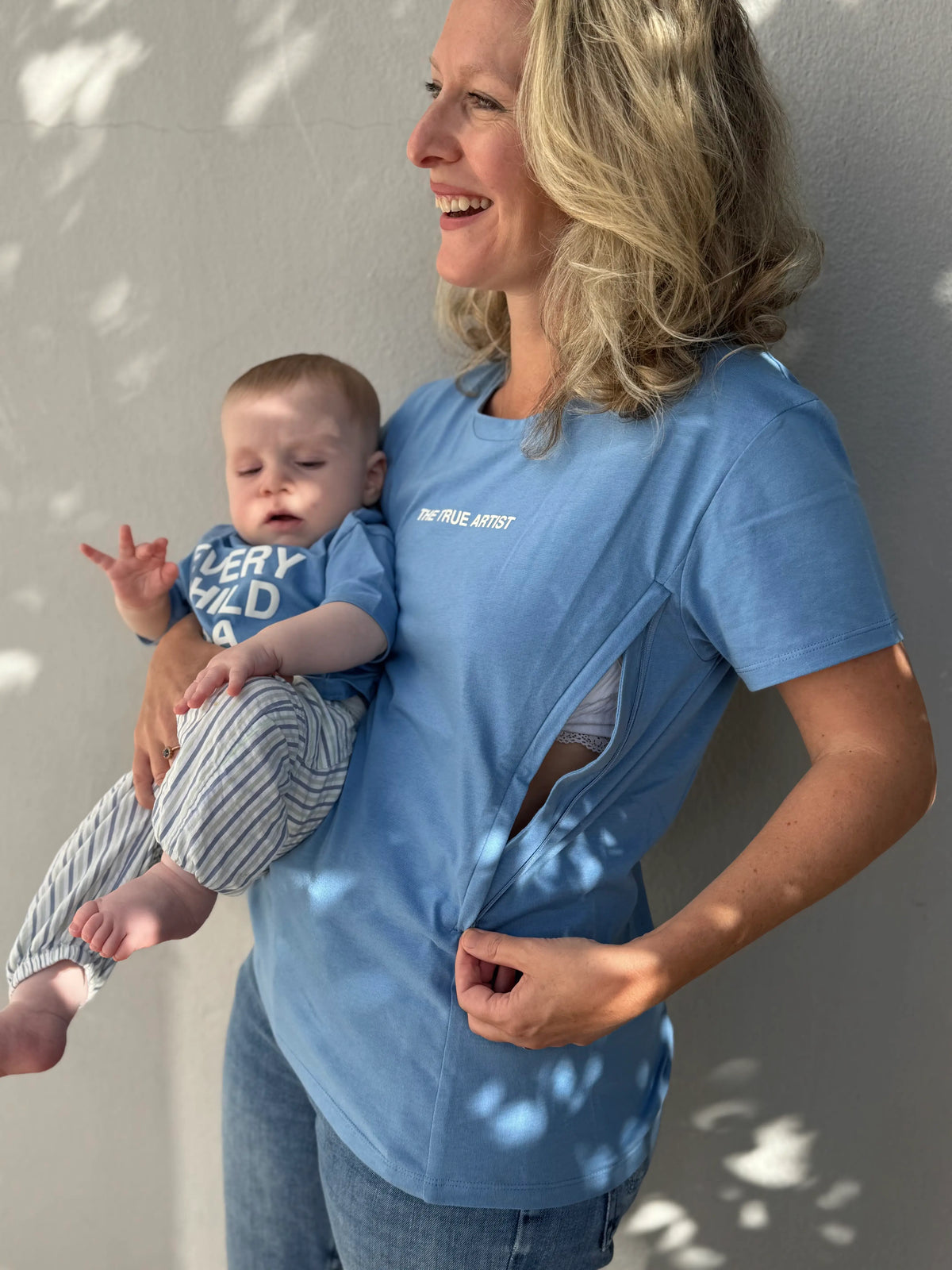 T-shirt d'allaitement LIMKY en coton bleu ciel, imprimé "tue true artist" avec des zips de chaque côté qui s'ouvre facilement à une seule main. Modèle assorti pour bébé "Every child is a masterpiece".
