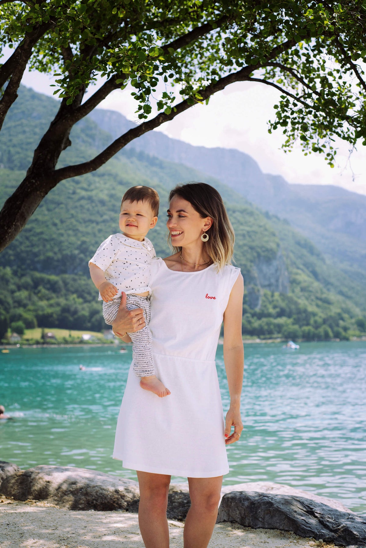 Robe d'allaitement blanche LIMKY, en coton et fabriqué au Portugal.
Cette robe avec un décolleté V dans le dos pour un dos nu est brodé au coeur "Love".
Cette robe maternité possède des longs zips solides, discrets et faciles à ouvrir d'une seule main pour nourrir bébé au sein rapidement, facilement et discrètement.
Un vêtement d'allaitement de qualité que les mamans auront plaisir à porter même après le post-partum. Une idée cadeau de naissance idéale à offrir pour une baby shower.