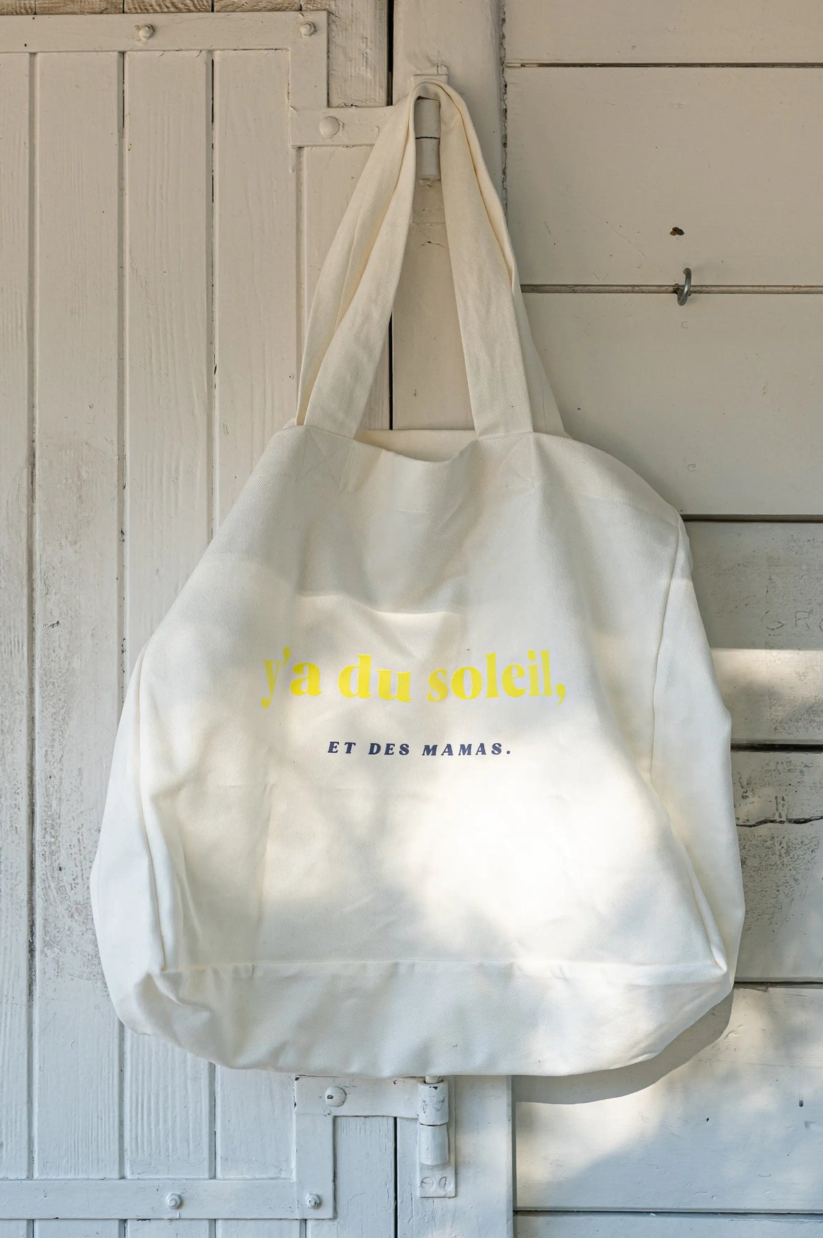 Sac à Langer  ou cabas XXL LIMKY. Ce fourre-tout 100% twill de coton est printé "Y'a du Soleil et des Mamas" pour un joli jeu de mot ensoleillé et vous accompagner pour toutes vos sorties : plage, bureau, ville, parc. Son format XXL permet à ce sac de contenir tous vos essentiels et indispensables de jeune maman de bébé.