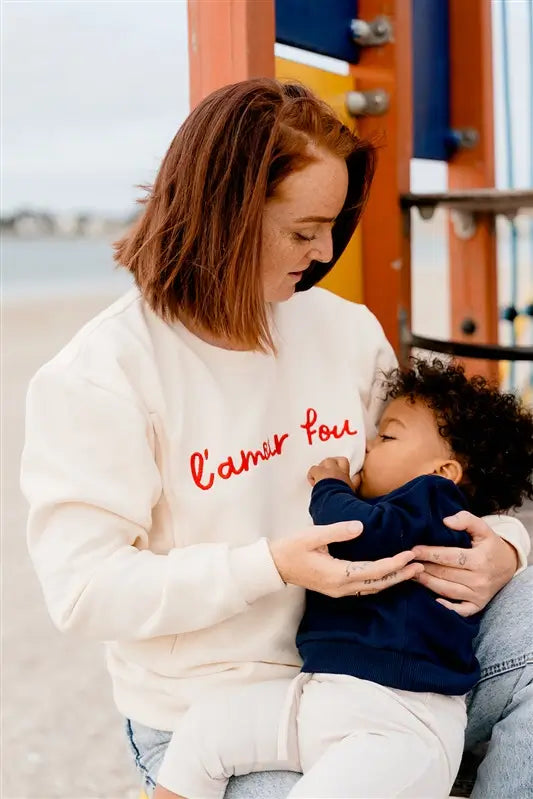 Sweat de Grossesse et Allaitement  LIMKY "L'Amour Fou". En coton, et doté de zips solides, discrets et faciles à ouvrir d'une seule main. Ce pull maternité de couleur crème est brodé "l'amour fou" en rouge. Sa coupe polyvalente et confortable donne un look tendance aux jeunes et futures mamans. Un vêtement maternité de qualité qui accompagne pendant la grossesse et l'allaitement, une idée de cadeau de naissance idéale pour sa liste de naissance ou une baby shower !