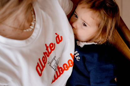 T-shirt d'allaitement blanc LIMKY "Alerte à Maliboob" en coton.
 Ce t-shirt au col rond est 100% coton et est fabriqué au Portugal.
Cet t-shirt maternité spécialement conçu pour faciliter l'allaitement, possède des longs zips solides et faciles à ouvrir d'une seule main pour nourir bébé au sein discrètement.
Un t-shirt original, tendance et de qualité que les mamans auront plaisir à porter même après le post-partum. Une idée cadeau de naissance idéale à offrir pour une baby shower.