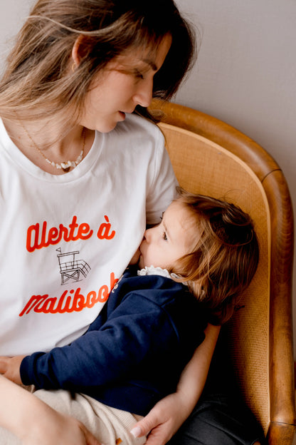 T-shirt d'allaitement blanc LIMKY "Alerte à Maliboob" en coton.
 Ce t-shirt au col rond est 100% coton et est fabriqué au Portugal.
Cet t-shirt maternité spécialement conçu pour faciliter l'allaitement, possède des longs zips solides et faciles à ouvrir d'une seule main pour nourir bébé au sein discrètement.
Un t-shirt original, tendance et de qualité que les mamans auront plaisir à porter même après le post-partum. Une idée cadeau de naissance idéale à offrir pour une baby shower.